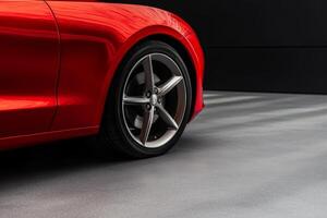 Red sports car parked on a modern surface with shadows highlighting its sleek lines and alloy wheels photo