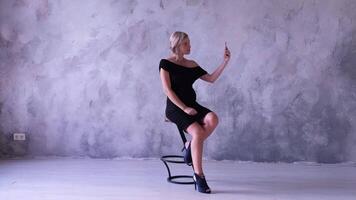 A woman in a black dress sitting on a stool video
