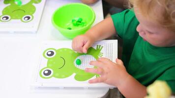 A child is playing with a frog on a board video