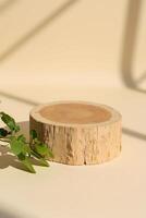 Natural wooden base with a smooth finish and green leaves for decoration placed on a light-colored surface in soft sunlight photo
