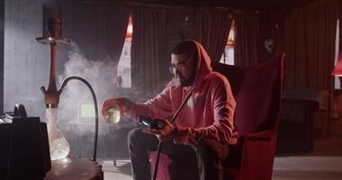 Man playing videogame and lounging with hookah in bar video