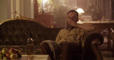 Perfumer drinking wine while sitting on vintage sofa at home video