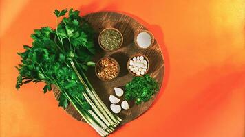 Fresh parsley, garlic, and assorted spices in wooden bowls on a rustic wooden plate against an orange background, perfect for food blogs, healthy eating promotions, or vibrant recipe visuals. photo