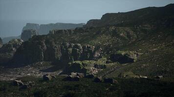 A view of a rocky mountain with green vegetation. mountain path video