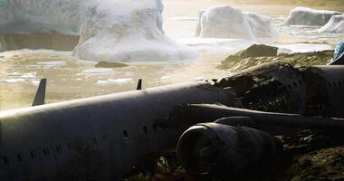 Wreckage of an aircraft on a remote shore near icebergs during sunset video