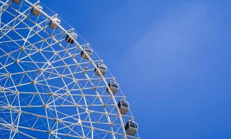 white Ferris wheel on background a bright blue sky in amusement park in summer with copy space photo