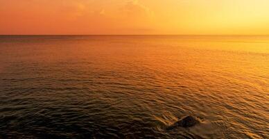 Sunset sky on sea ocean with soft motion blur of ripples on top surface texture with yellow, orange sunlight reflection on water,Summer sea beach with shimmering golden reflection on water texture photo