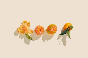 Fresh tangerines on beige background with sunlight shadows, minimal aesthetic citrus fruits as summer food background, organic orange colored mandarin with green leaves top view, copy space photo