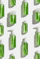 Cosmetic products with green liquid for skin treatment, beauty routine, skin health. Minimal creative pattern with lotion, tonic, micellar water mockup with sun shadow, minimal aesthetic flat lay photo