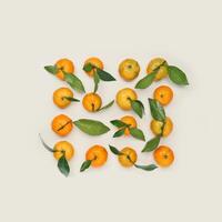 Set of Tangerines as minimal creative pattern, Ripe fresh orange yellow fruits with green leaves on beige background. Citrus mandarines as still life food, flat lay style, summer aesthetic photo