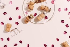Pattern of champagne corks and bright confetti on pastel color background with sunlight shadow, sun glare. Trend layout of bottle cap cork, top view, minimal flat lay, holiday, celebrate concept photo