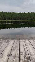 Tranquil lakeside view with wooden pier and lush forest under overcast sky photo