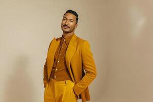Confident young hispanic male in stylish brown suit posing against neutral background photo