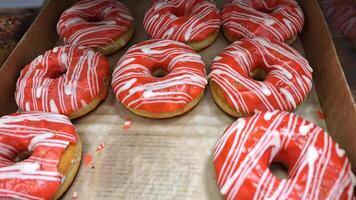 Vibrant red iced donuts with white drizzle arrangement in cardboard box photo