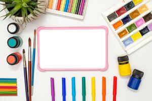 pink digital tablet on a white table, multicolor drawing supplies. photo