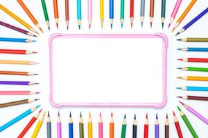 digital tablet on a white table with a frame of colored pencils photo
