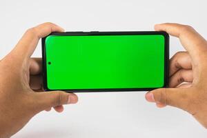 Hands Holding Smartphone with Green Screen on White Background for Technology or Display Mockup photo
