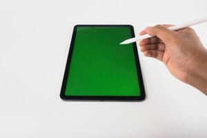 Hand Using Stylus On Tablet With Green Screen Display photo