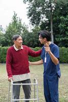 Supportive caregiver sharing a moment with elderly man using walker, fostering connection and well-being in a vibrant garden photo