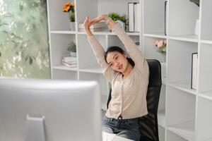 Woman stretching and relieving tension at her office desk during work. photo