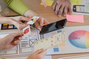 Hands-on team brainstorming app prototypes and design elements at a workspace. photo
