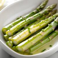 Freshly cooked asparagus served with olive oil and herbs in a bowl. photo