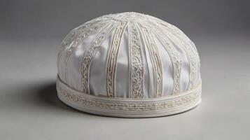 A photo of a neatly folded white kufi cap with delicate embroidery patterns.