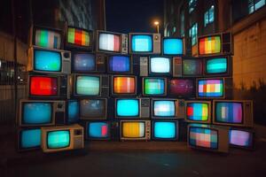 Stack of vintage televisions displaying colorful test patterns at night photo