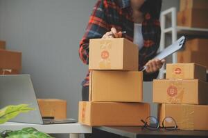 A woman is standing in front of boxes and a laptop photo