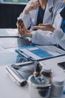 Two doctors are sitting at a table with a tablet and a bottle photo