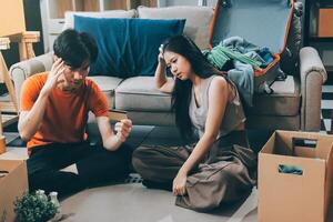 A man and woman sitting on the floor with boxes and a suitcase photo