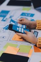 A person is using a smartphone on a table with paper and other items photo