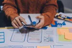 A person is using a cell phone while sitting at a desk with a bunch of paper and other photo