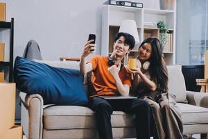 A couple sitting on a couch with a phone and orange juice photo