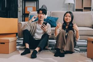 Asian couple sitting on the floor with boxes and a phone photo