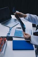 A doctor is working on a laptop and a tablet photo