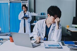 A doctor is sitting at a desk with a laptop photo