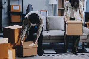 Two people moving boxes in a living room photo