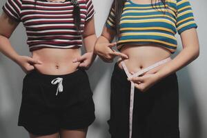 Two women in striped tops holding measuring tape photo
