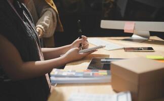 A person is writing on a piece of paper while sitting at a desk photo