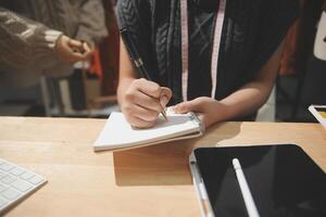 A person is writing on a notebook while sitting at a desk photo