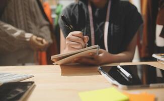 A woman is writing in a notebook while sitting at a desk photo