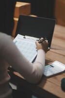 A woman writing on a notebook and using a pen on a table photo