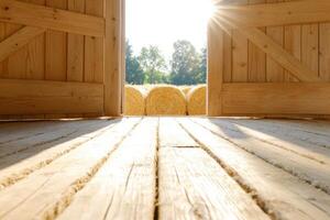 Stepping into a rustic barn with warm sunlight illuminating stacked hay bales on a tranquil afternoon photo