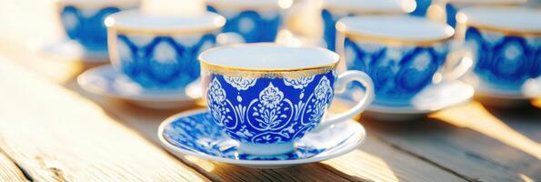 Intricate blue porcelain tea cups arranged elegantly on a wooden table bathed in soft golden light during a serene afternoon setting photo