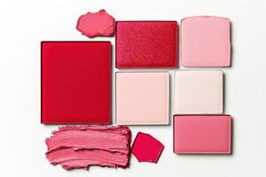 Flat lay arrangement of red and pink makeup essentials featuring eye shadow palettes and lipsticks on a minimalistic surface photo