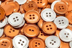Close-up view of shiny metallic orange and silver buttons showcasing intricate textures and warm lighting effects photo