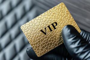 Golden VIP membership card held by a hand in a black glove, showcasing exclusivity and high status in an upscale setting photo