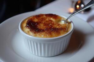 Spoon digging into a small bowl of creme brulee photo