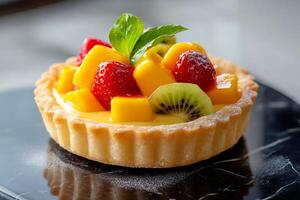 Delicious fruit tart with mango, kiwi and strawberries garnished with mint leaf photo